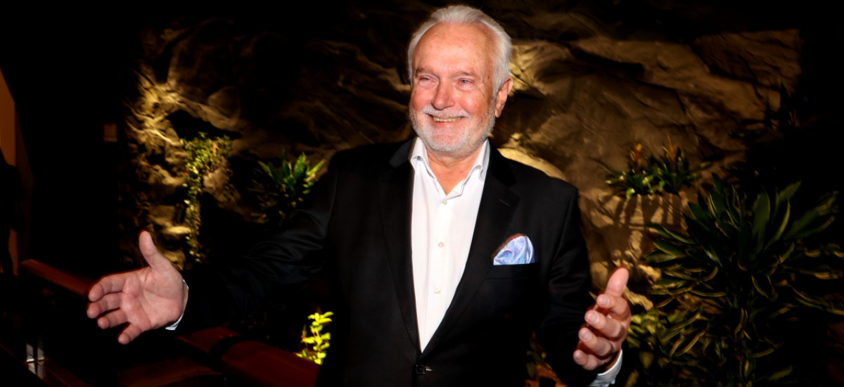 Foto von Wolfgang Kubicki in festlichem Ambiente, der mit seinen Armen eine einladende Geste macht