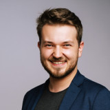 Florian Lipp junger lächelnder Mann mit kurzen braunen Haaren, einem blauen Sakko und T-shit.