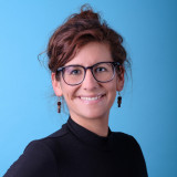 Frau, braune Locken, Brille, lächelt