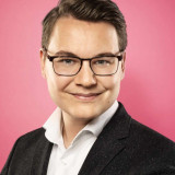 Das Bild zeigt den Landtagskandidaten der SPD, Philipp Göhner, vor einem roten Hintergrund.