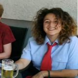 Angelina Schüller Hübsche junge Frau mit tollen Locken. Einer roten Krawatte um den hals und einen kleinen Humpen Bier in der Hand.