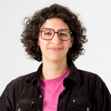 Pilar Caballero Alvarez Die Kandidierende Pilar lächelt frontal. Sie hat eine rote eckige Brille an und lockige, kurze Haare.