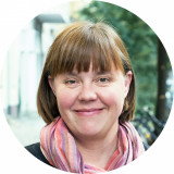 Catrin Wahlen Das Bild zeigt eine lächelnde Frau Wahlen, im Hintergrund ist eine Straße und ein Baum zu erahnen
