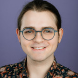 Colin Rimbach Ein Portrait des Direktkandidaten Colin Rimbach, auf welchem dieser vor lila Hintergrund zuversichtlich lächelt.