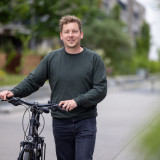 Auf dem Foto ist Pascal Mennen zu sehen, der ein Fahrrad schiebt.