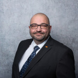 Porträt von Martin Rössler, AfD-Direktkandidat WK43 – Neustadt, im dunklen Anzug mit Krawatte vor grauem Hintergrund.