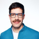 Auf dem Bild ist Moritz Warnk zu sehen, er trägt ein weißes Shirt und darüber eine blaue Jacke.