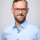 Tim Detzner Bild zeigt Kandidaten Tim Detzner in einem blauen Hemd, mit Brille. Er lächelt.