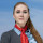 Frau mit langen, roten Haaren, blauer Bluse, grauem Blazer und rotem Halstuch