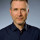 Michael Voigt Ein Porträtbild von Michael Voigt, Geschäftsführender Gesellschafter, in einem professionellen Umfeld. Er trägt ein dunkles Sakko und ein Hemd, und lächelt freundlich in die Kamera.