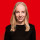 Sabrina Repp Die Europaabgeordnete Sabrina Repp hat lange blonde Haare und ein schwarzes Oberteil an. Sie lächelt auf dem Bild, das einen roten Hintergrund hat.