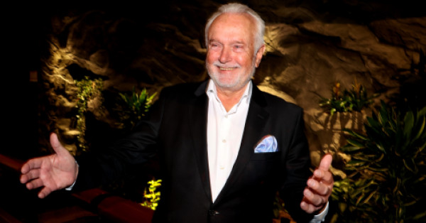 Foto von Wolfgang Kubicki in festlichem Ambiente, der mit seinen Armen eine einladende Geste macht