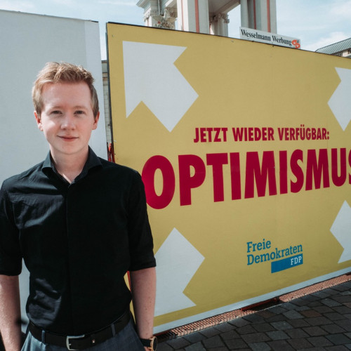 Matti Karstedt vor einem Großflächenplakat der FDP Brandenburg