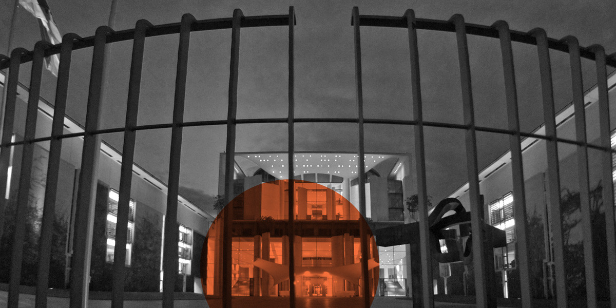 Blick durch einen Zaun auf den beleuchteten Eingang des Kanzleramts