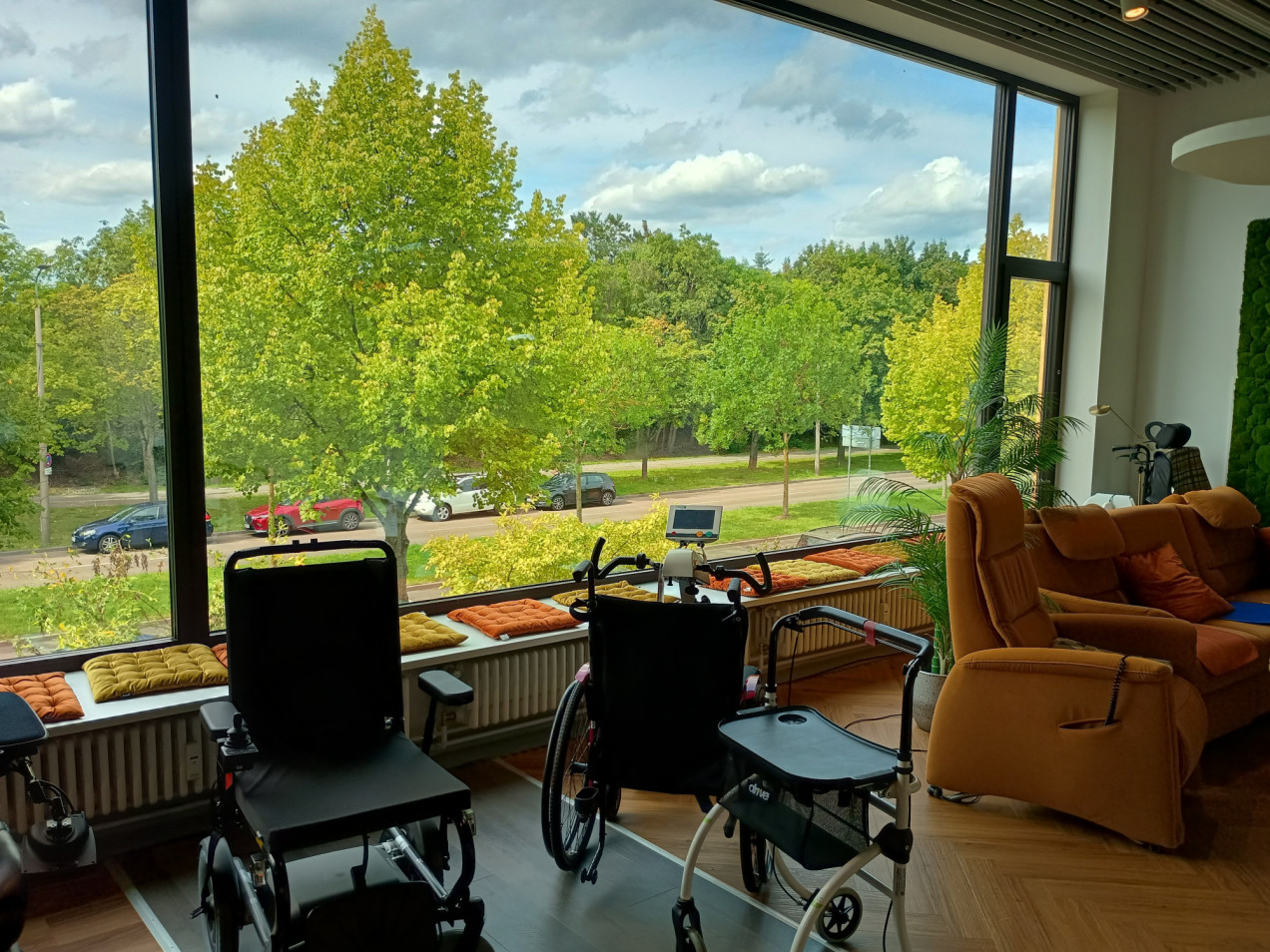 Blick aus dem SLHC, man sieht Sofas, Rollstühle, hinter dem Fenster Straße und grüne Bäume.