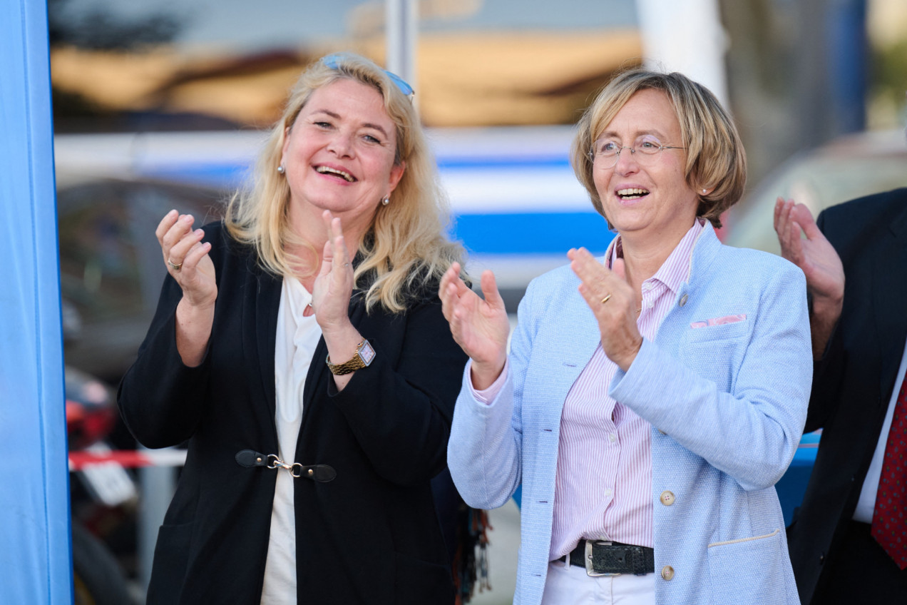 Kristin Brinker steht neben Beatrix von Storch, beide klatschen in die Hände und lachen